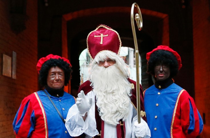 Saint Nicholas poses with his two assistants called "Zwarte Piet" during a traditional parade in central Brussels
